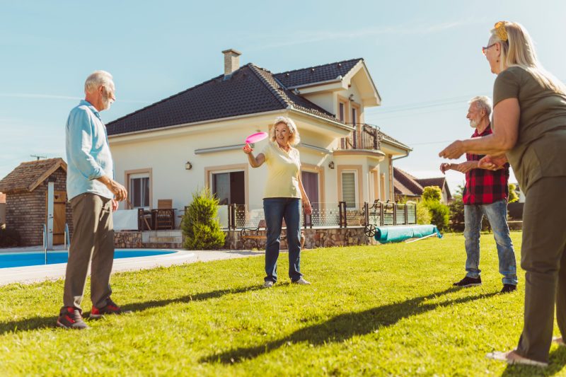 Group of active senior people having fun spending sunny summer day outdoors, playing catch and toss